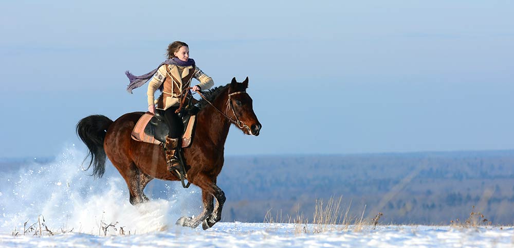 Woman galloping through the snow.