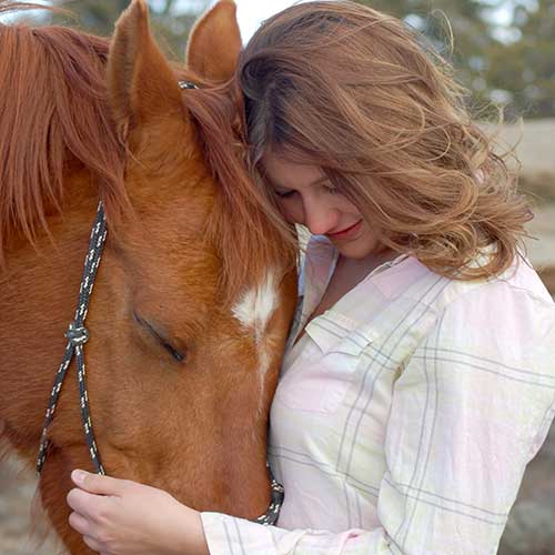 Horseback rider hugging her horse.